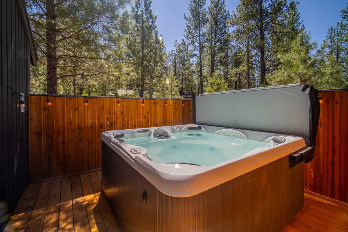 This serene exterior image spotlights a bubbling hot tub surrounded by trees and a wooden fence—a tranquil retreat after a day of adventure. It captures the relaxing, restorative side of Sunflower, especially in winter after a day spent skiing or exploring the outdoors.