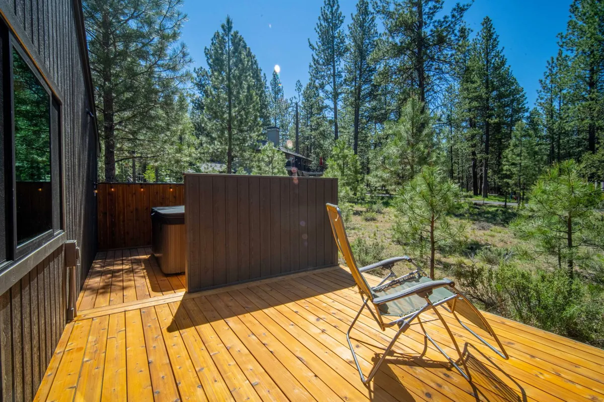 A wooden deck with a lounge chair gazing out into dense, peaceful forest, emphasizing privacy and a close connection with nature. The scene invites thoughts of night skies, quiet reflection, and immersion in the outdoors.
