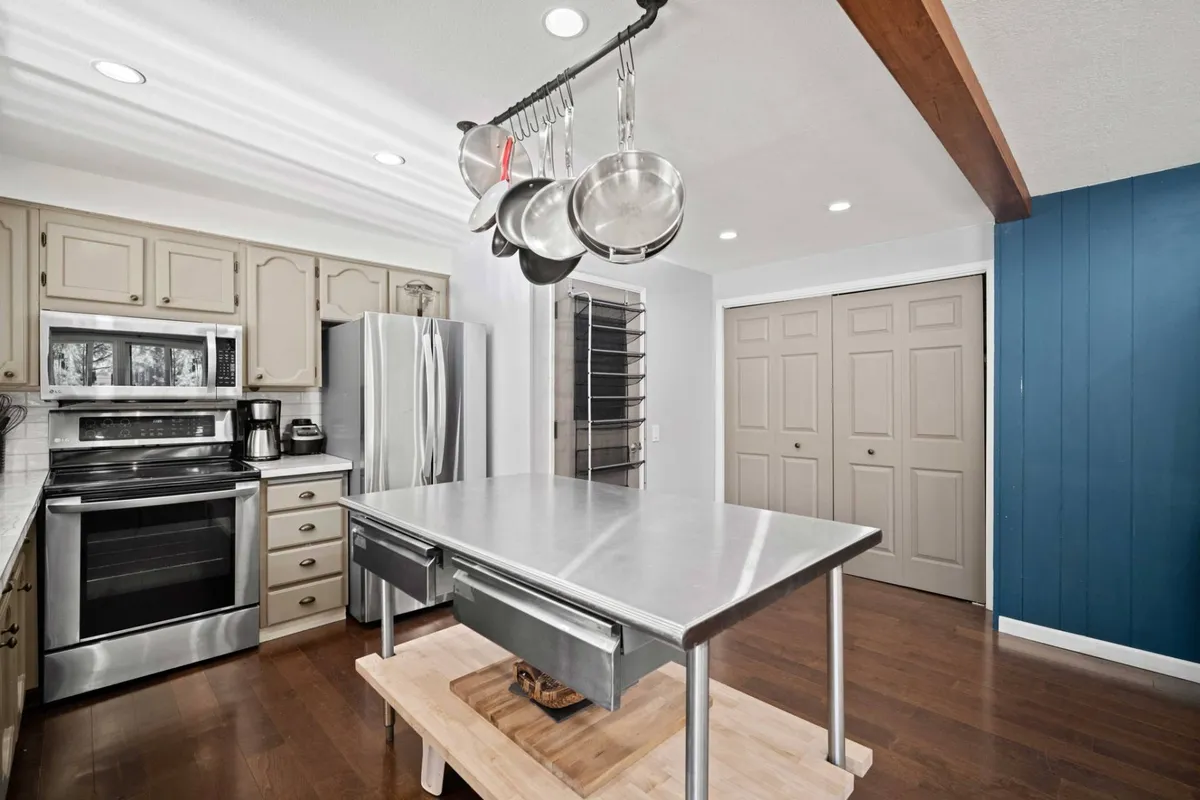 A modernized kitchen scene showcasing stainless steel appliances, a spacious kitchen island, and various cooking utensils within easy reach. The environment feels practical and inviting, ideal for group meal prep and entertaining.