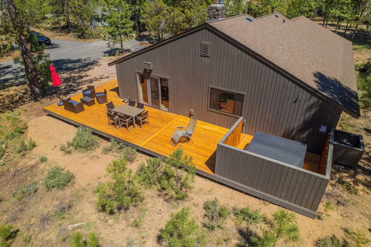 An exterior scene featuring a cozy deck area with comfortable outdoor seating and a bubbling hot tub, framed by natural scenery. The setup encourages relaxation, socializing, and enjoying the outdoors in privacy.